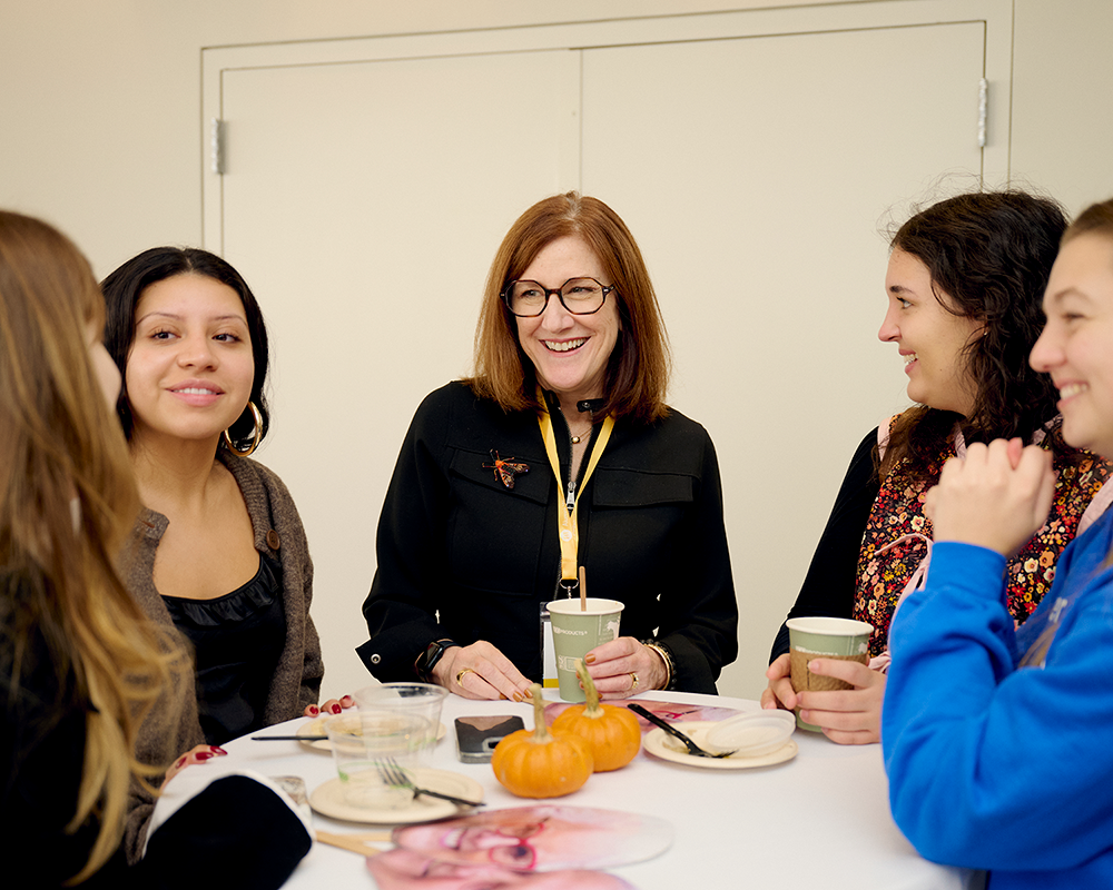 a group of students speaking with faculty at a daytime social