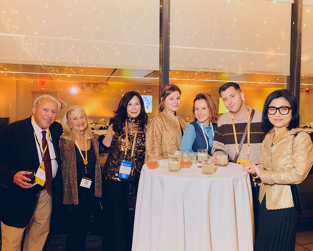 group photo of alumni and faculty posing for a group photo behind a high top table