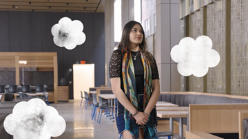 A female student standing in the New Academic Building with clouds surrounding her to show that she is dreaming