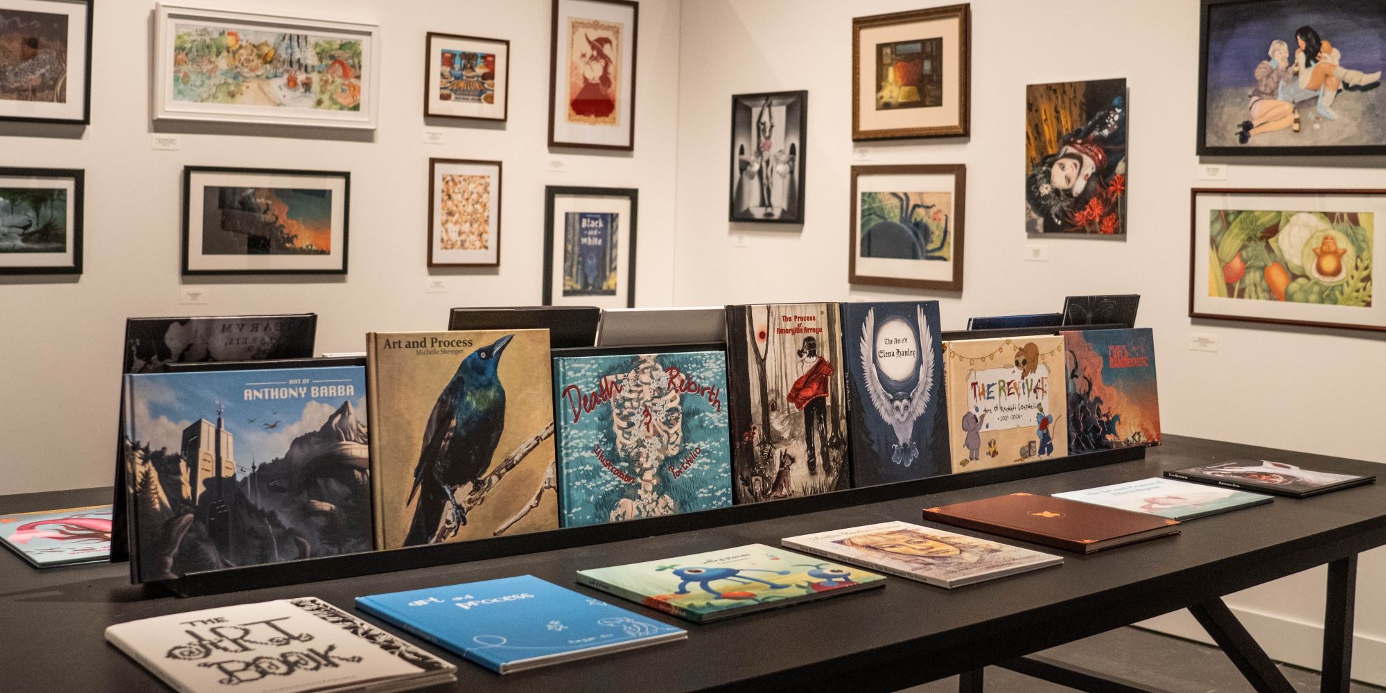 multiple illustrated books displayed on the table, and framed illustrations hung on the two walls