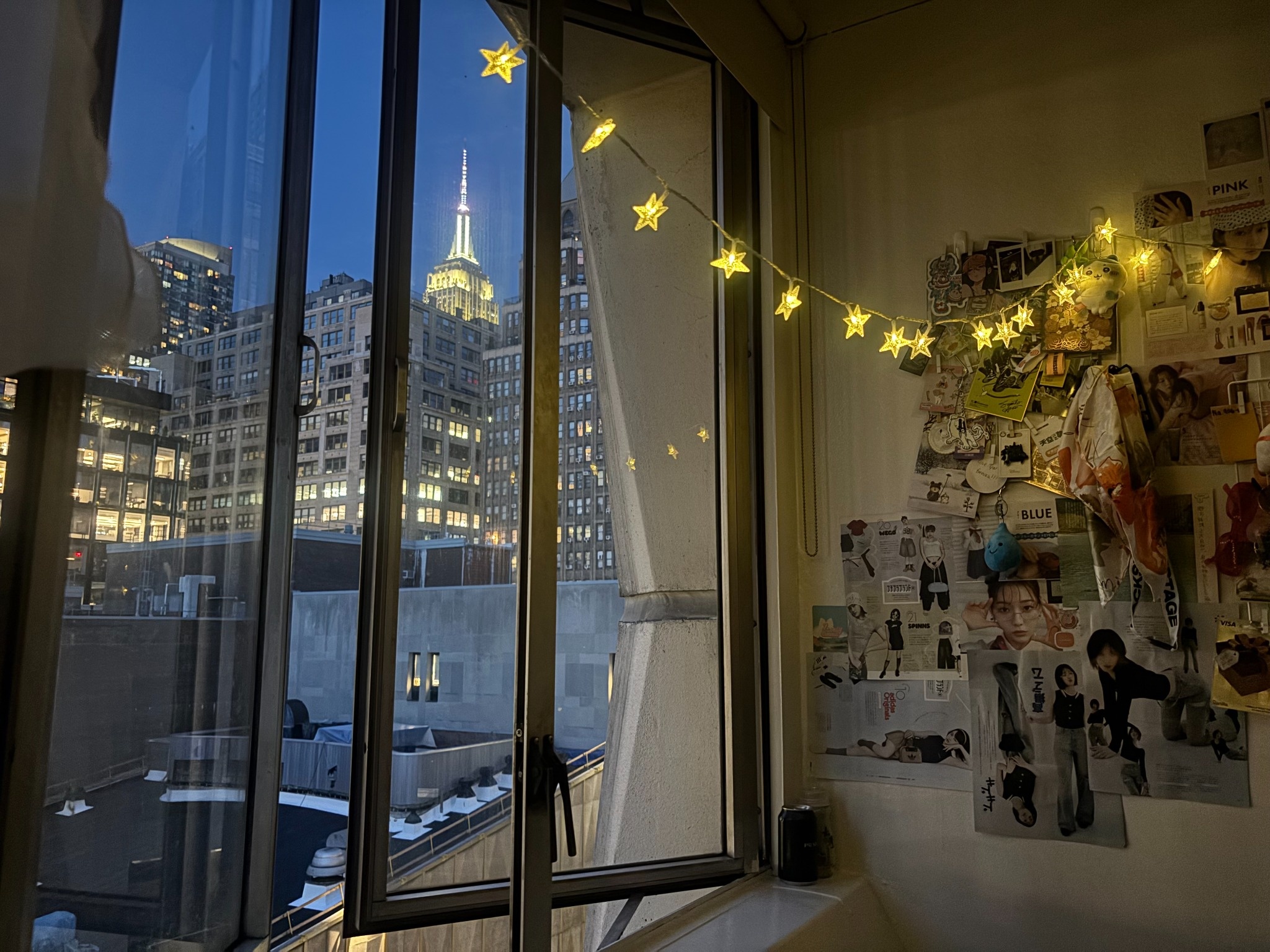 Looking out a window at night to a lite up Empire State Building