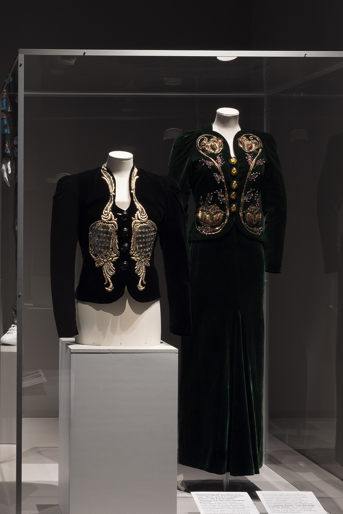 black suit jacket with angel wing made of mirror shards and green suit and skirt set