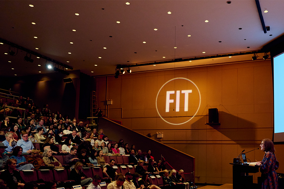 Guests seated in Katie Murphy Amphitheatre listen to a presenter at a podium.