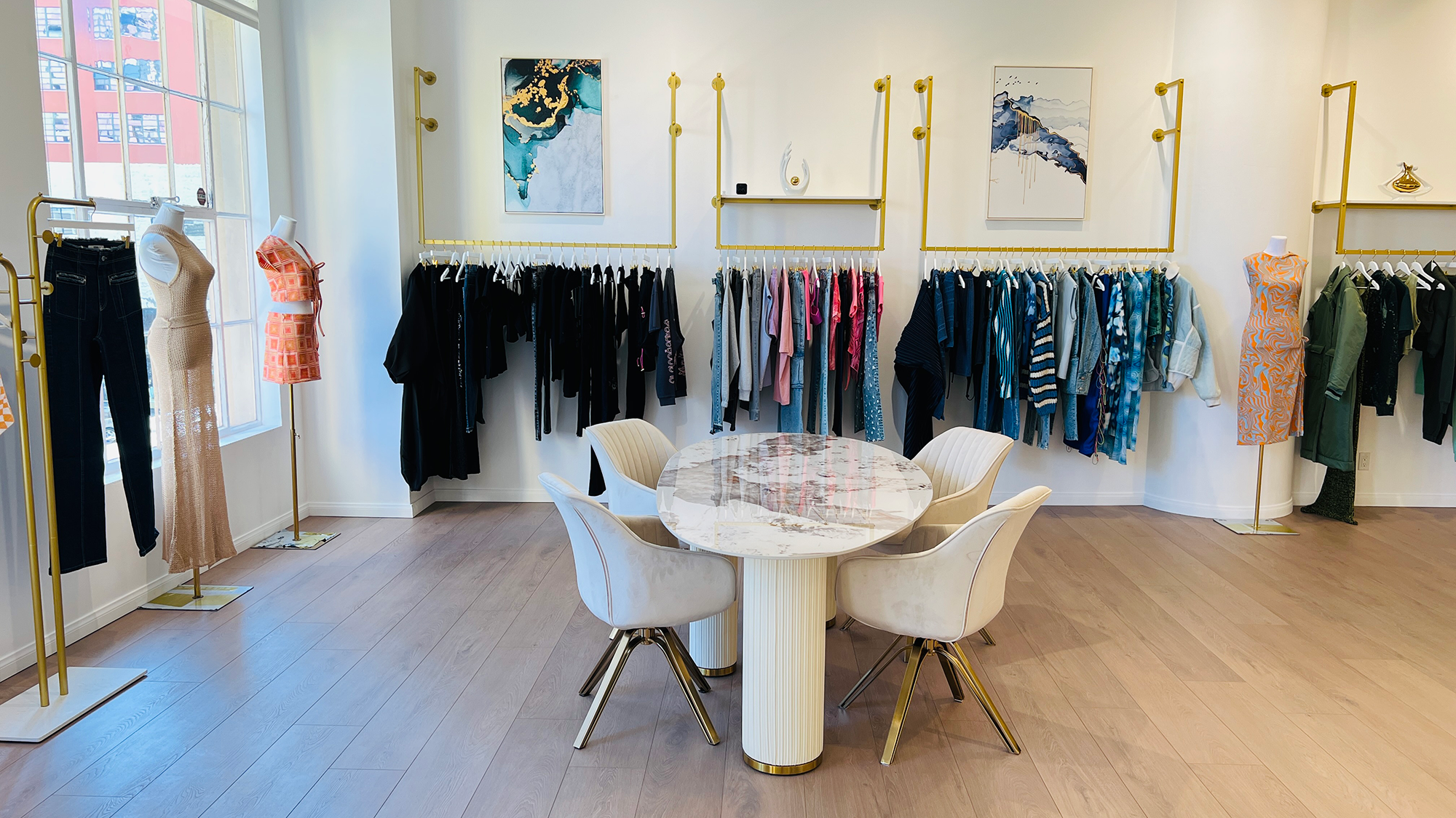 GBS Trend showroom with displays of clothing on hanging rack and marble table in center