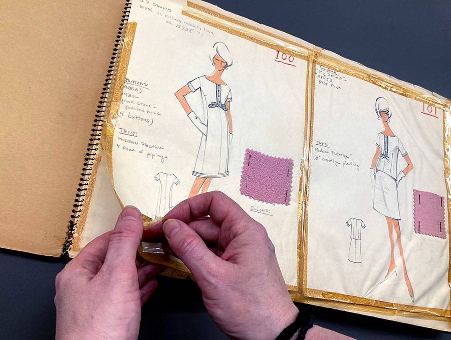 A person's hands pulling old tape off a fashion sketch