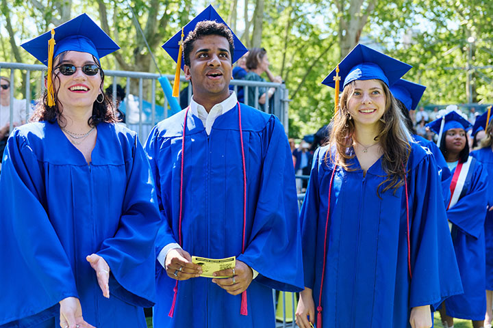 three students in blue regalia smiling 