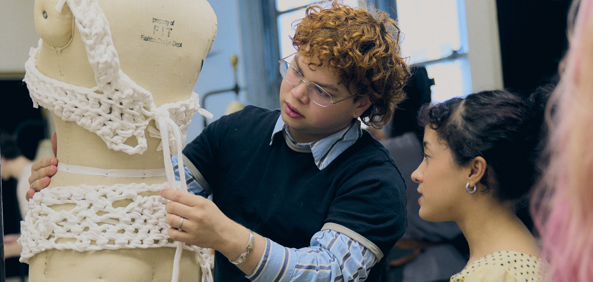 students looking at knitted clothing on a dress form