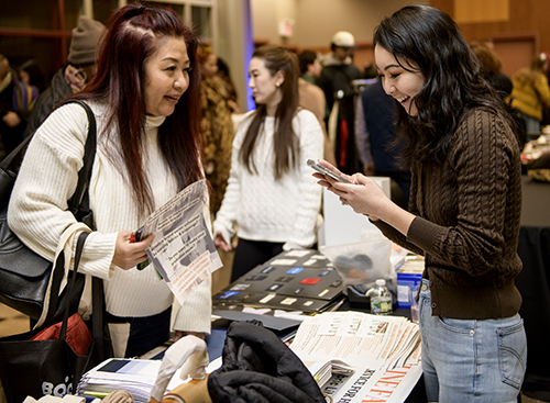 Two female attendees at a vendor's table