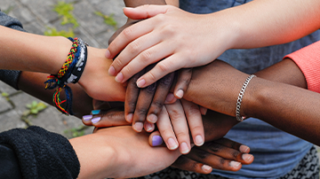 several people's hands placed on top of another to show unity
