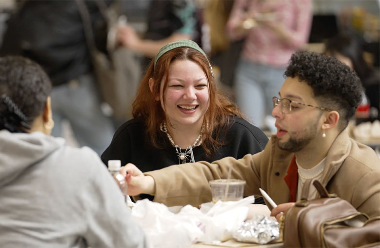 Students sitting at a table in the dining hall laughing