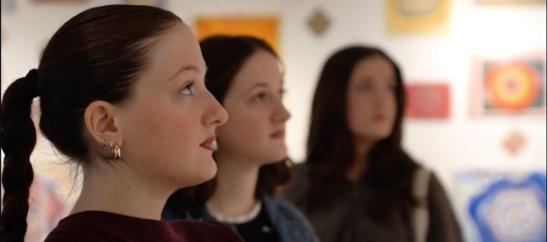 Three sisters standing looking at artwork