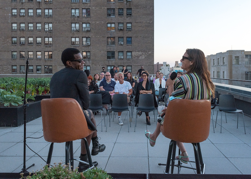 rooftop event with two speakers in chairs addressing a seated audience