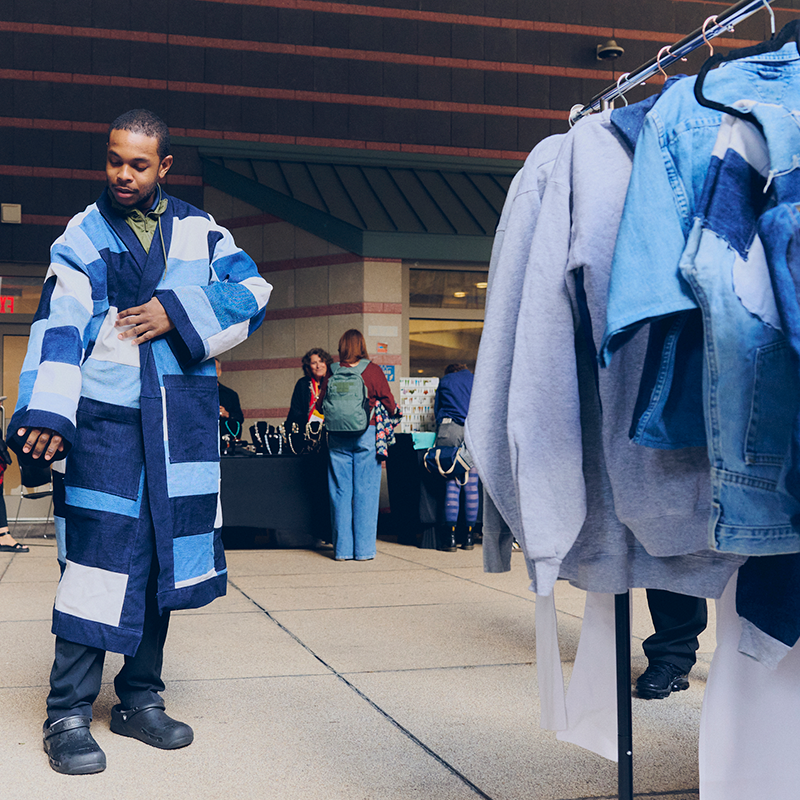A customer tries on a patchwork denim jacket at the Alumni Bazaar
