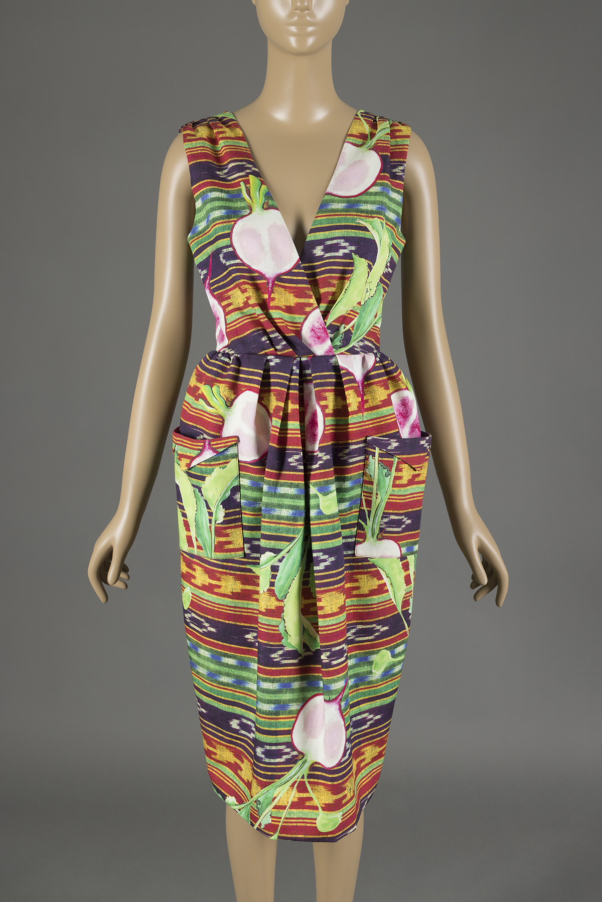 Beige mannequin with a V-neck sleeveless dress in green, red, yellow, and purple stripes with a radish print. 