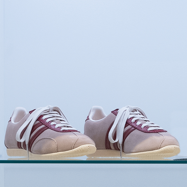 beige sneakers with dark red stripes and white laces
