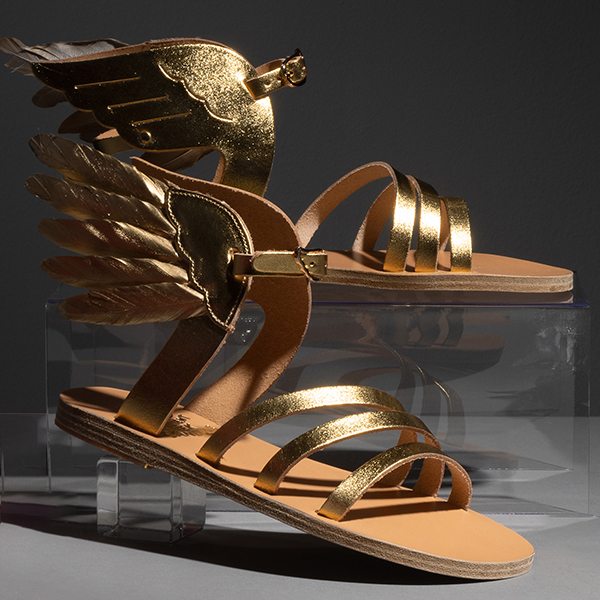 Gold leather strappy flat sandals with wing details at the heel