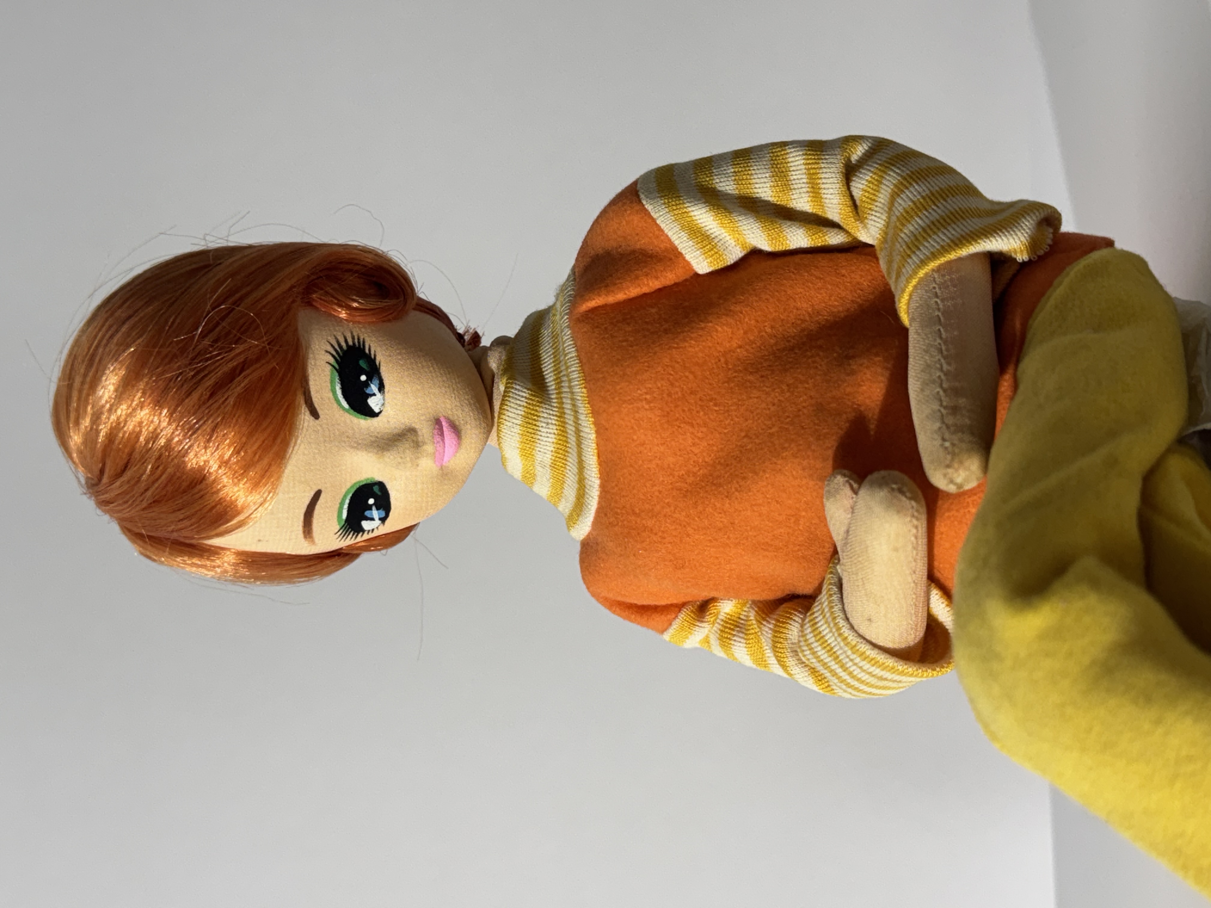 detail shot of 1960s doll with short orange hair, posed in a seated position